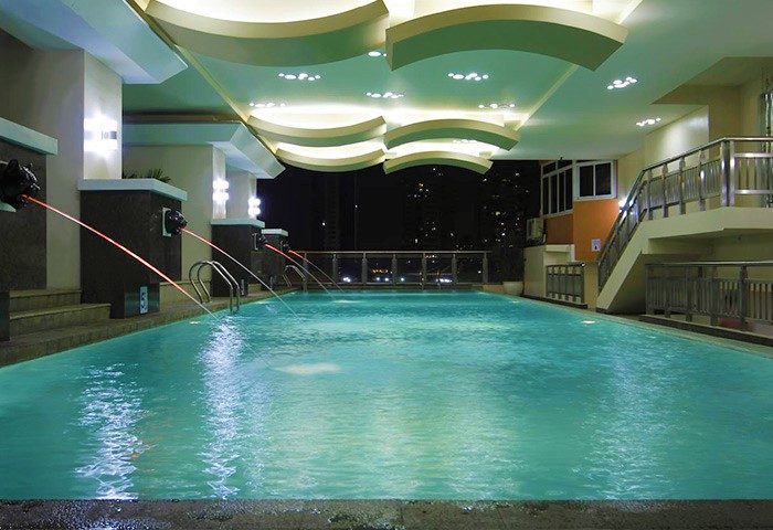 Regency Grand Suites gay-friendly hotel pool at night. Lion head fountains, city view. Relaxing luxury for gay travelers.