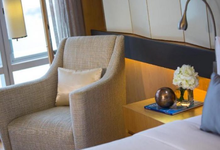Renaissance Hong Kong Harbour View Hotel room detail. Armchair, bedside table with flowers and lamp. Gay-friendly hotel for gay men travelers.