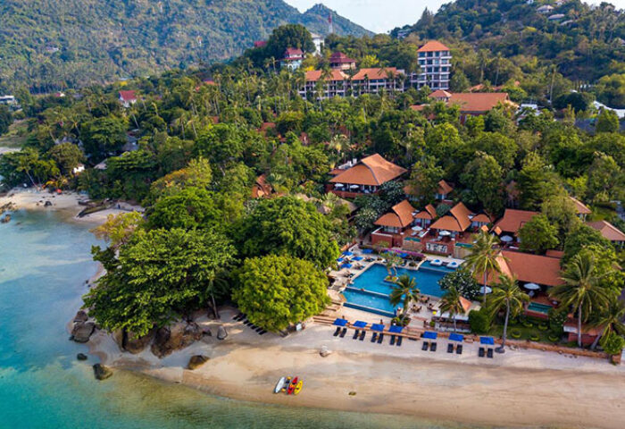 Gay-Friendly Renaissance Koh Samui Resort & Spa aerial view. Beachfront hotel with pool, lush greenery, and mountain backdrop. Thailand resort.