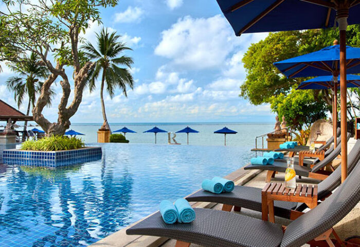 Renaissance Koh Samui Resort & Spa pool view. Gay-friendly hotel with beach umbrellas, palm trees, and lounge chairs for relaxing vacation.
