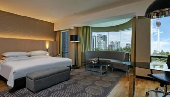 Renaissance Kuala Lumpur Hotel & Convention Centre room. Gay-friendly hotel with city view. King bed, sofa, desk, and KL Tower visible.