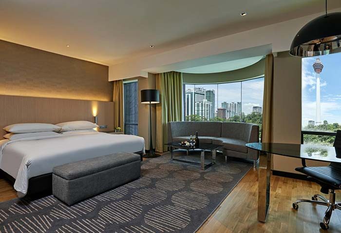 Renaissance Kuala Lumpur Hotel & Convention Centre room. Gay-friendly hotel with city view. King bed, sofa, desk, and KL Tower visible.