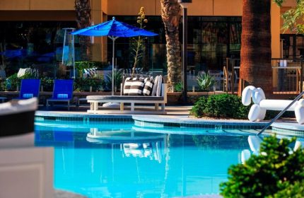 Poolside at Renaissance Palm Springs Hotel, a gay-friendly hotel. Blue umbrella, lounge chairs, and a whimsical balloon dog statue add to the resort's charm.