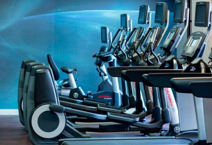 Gay-Friendly Renaissance Palm Springs Hotel gym. Treadmills, ellipticals, and stationary bikes for guests' fitness. Hotel gym with blue wall.