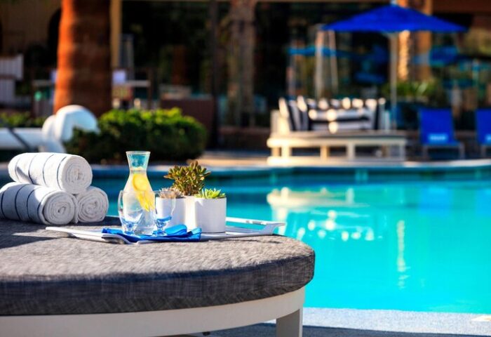 Poolside view at the gay-friendly Renaissance Palm Springs Hotel. Towels, water, and plants sit on a table near the pool.