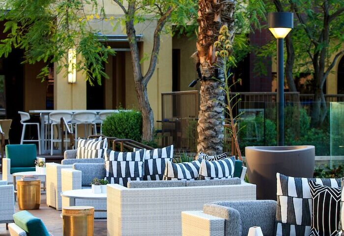 Renaissance Palm Springs Hotel outdoor lounge area. Gay-friendly hotel with stylish seating, tables, and palm trees. Perfect for relaxing.