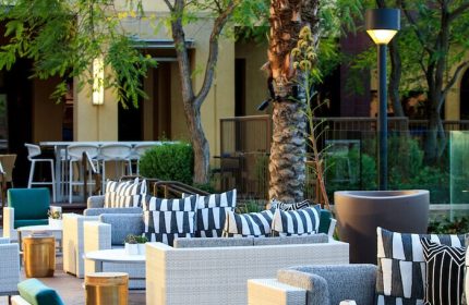 Renaissance Palm Springs Hotel outdoor lounge area. Gay-friendly hotel with stylish seating, tables, and palm trees. Perfect for relaxing.