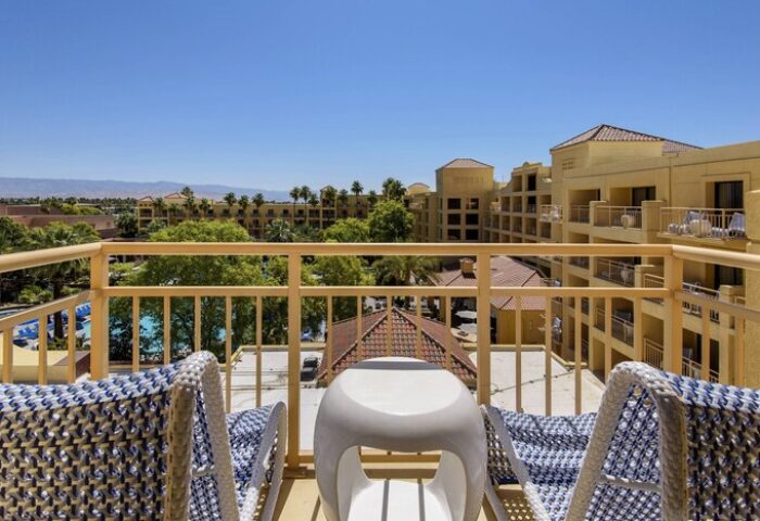 Balcony view at the gay-friendly Renaissance Palm Springs Hotel. Lounge chairs overlook the pool and Palm Springs landscape. Relaxing vacation.