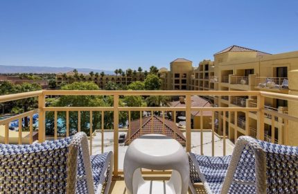 Balcony view at the gay-friendly Renaissance Palm Springs Hotel. Lounge chairs overlook the pool and Palm Springs landscape. Relaxing vacation.