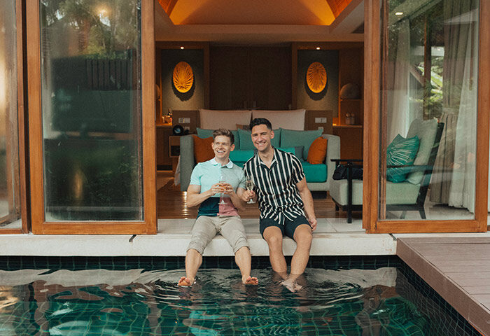 Gay couple at Renaissance Phuket Resort & Spa. Men relax by private pool with champagne. Gay-friendly hotel for travel advice.