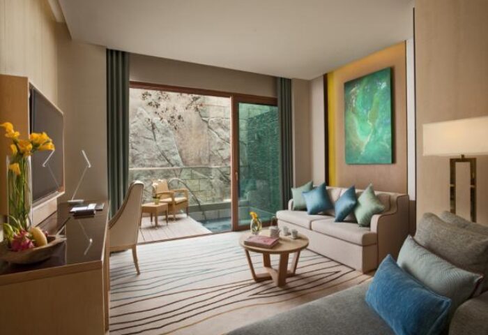 Resorts World Sentosa Beach Villas interior. Gay-friendly hotel room with balcony, seating area, desk, and modern design. SG Clean Certified.