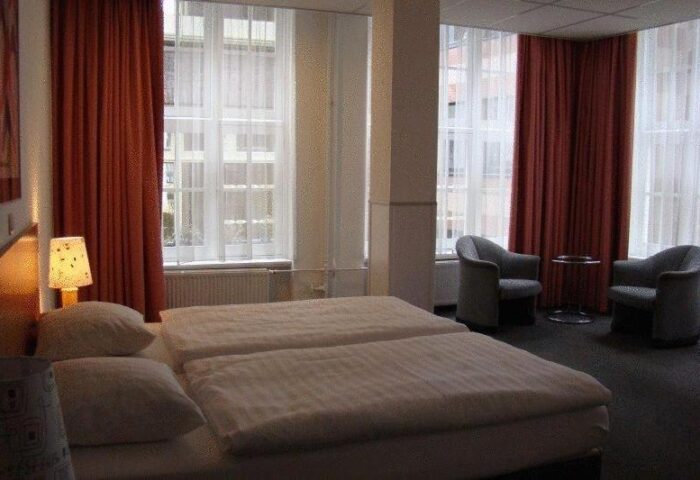 Bedroom at Gay-Friendly Rho Hotel. Room with twin beds, chairs, and large windows. A comfortable choice for gay travelers.
