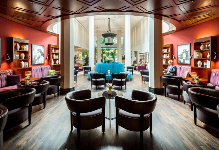 Lobby lounge at Rocco Forte The Charles Hotel, a gay-friendly hotel. Stylish seating, bookshelves, and a turquoise central seating area.