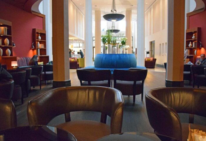 Lobby lounge at Rocco Forte The Charles Hotel, a gay-friendly hotel. Brown leather chairs, blue sofa, and bookshelves. Upscale Munich hotel.