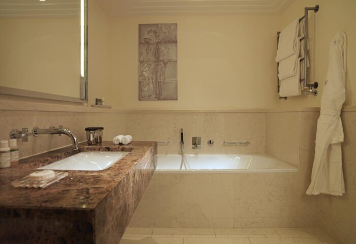 Bathroom at Rocco Forte The Charles Hotel, a gay-friendly hotel. Sink, bath, towels, and robe in a luxurious setting. Ideal for gay travel.
