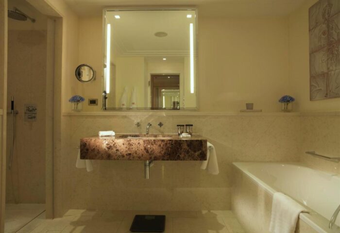 Bathroom at Rocco Forte The Charles Hotel, a gay-friendly hotel in Munich. Features a marble sink, bathtub, and walk-in shower.
