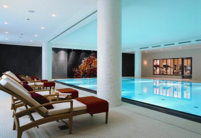 Indoor pool at Rocco Forte The Charles Hotel, a gay-friendly hotel. Loungers line the pool, offering a relaxing space for guests.