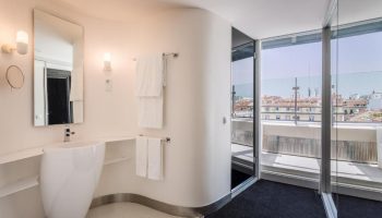 Room Mate Oscar hotel bathroom with modern sink, mirror, and balcony. Gay-friendly hotel design in Madrid. Great view from the room.