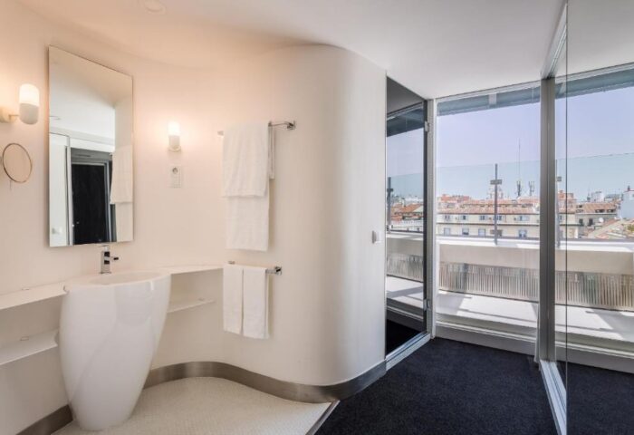 Room Mate Oscar hotel bathroom with modern sink, mirror, and balcony. Gay-friendly hotel design in Madrid. Great view from the room.