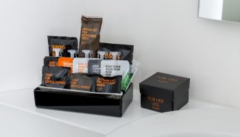 Room Mate Oscar Hotel bathroom amenities. Gay-friendly hotel features toiletries like soap, shampoo, shaving kit, dental kit, body scrub, and shower cap.