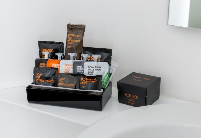 Room Mate Oscar Hotel bathroom amenities. Gay-friendly hotel features toiletries like soap, shampoo, shaving kit, dental kit, body scrub, and shower cap.