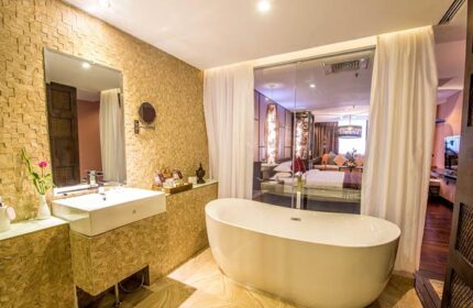 Bathroom at gay-friendly Rose Garden Hotel. Bathtub, sink, mirror, and view into bedroom. Luxury hotel for gay men travel.