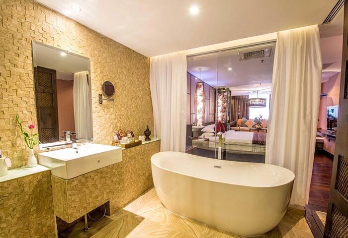 Bathroom at gay-friendly Rose Garden Hotel. Bathtub, sink, mirror, and view into bedroom. Luxury hotel for gay men travel.