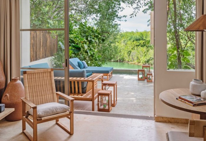 Rosewood Mayakoba gay-friendly hotel suite view. Outdoor seating, pool, and lush greenery. Luxury travel for gay men in Riviera Maya.