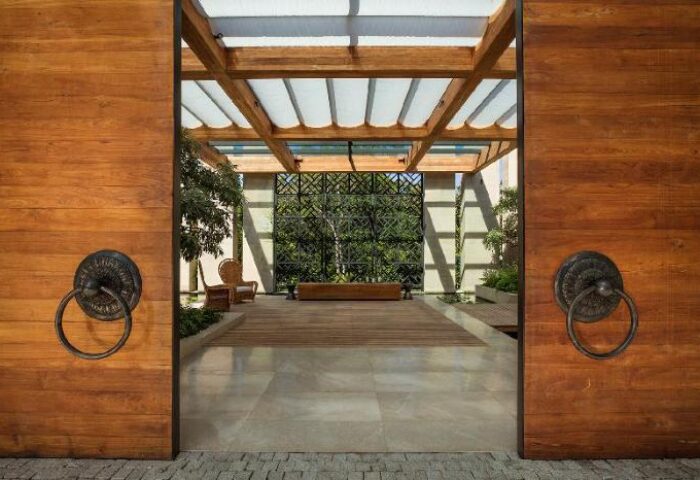 Rosewood Phuket gay-friendly hotel entrance. Large wooden doors with ring handles open to a serene garden space. Luxury gay travel in Thailand.