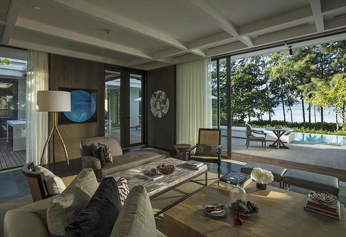 Rosewood Phuket gay-friendly hotel suite featuring a living room with sofas, coffee tables, and an outdoor terrace with a pool and ocean view.