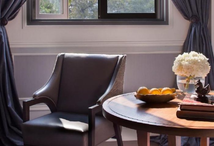 Rosewood Yangon gay-friendly hotel room. Pet-friendly with chair, table, fruit, flowers, and decor. Luxury travel for gay men in Myanmar.