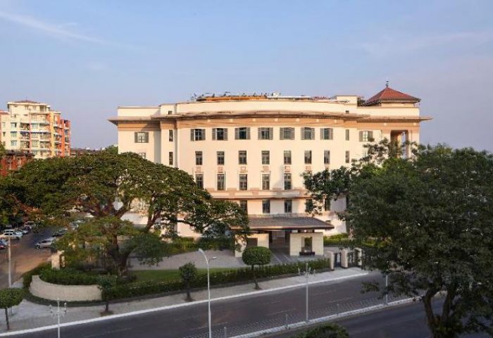Rosewood Yangon, a gay-friendly and pet-friendly hotel. Exterior view of the luxury hotel in Yangon, Myanmar, with trees and street.