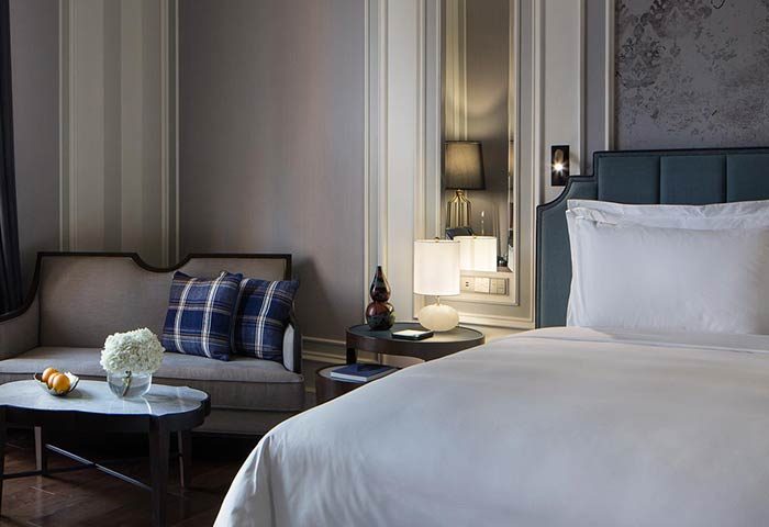 Rosewood Yangon gay-friendly hotel room. Pet-friendly suite with bed, couch, and table. Elegant decor for LGBTQ+ travelers in Yangon.