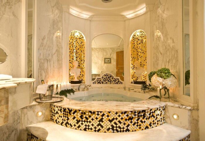 Royal Olympic Hotel gay-friendly bathroom. Marble, gold mosaic tiles, tub, champagne, and busts create a luxurious experience for gay travelers.