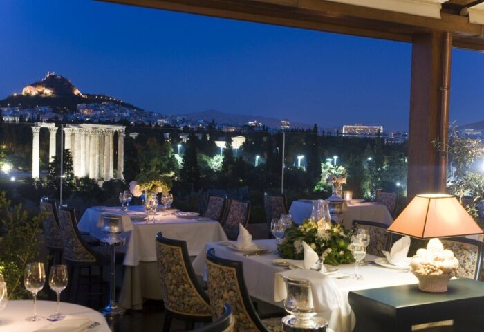 Royal Olympic Hotel gay-friendly restaurant at night with Acropolis view. Fine dining experience for gay men travelers in Athens, Greece.
