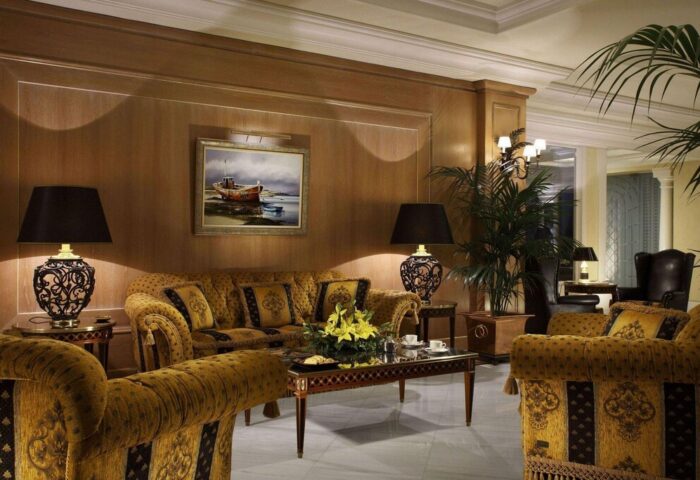Royal Olympic Hotel's gay-friendly lounge area. Elegant seating, lamps, painting, and plants create a luxurious, welcoming atmosphere.