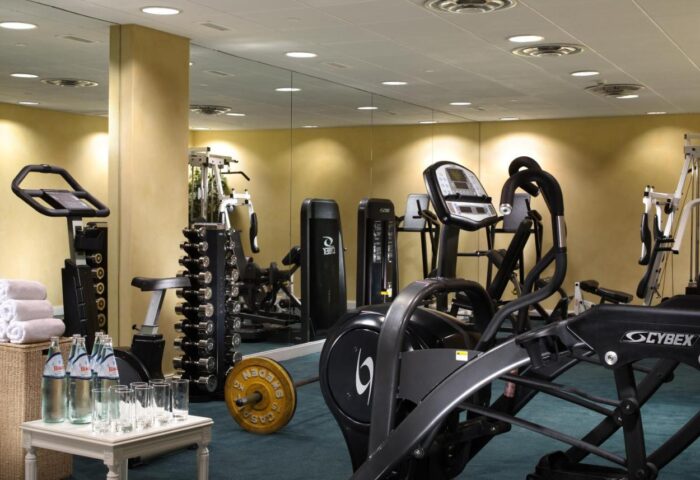 Royal Olympic Hotel gym. Fitness center with weights, cardio machines, water bottles, and towels. Gay-friendly hotel amenity.