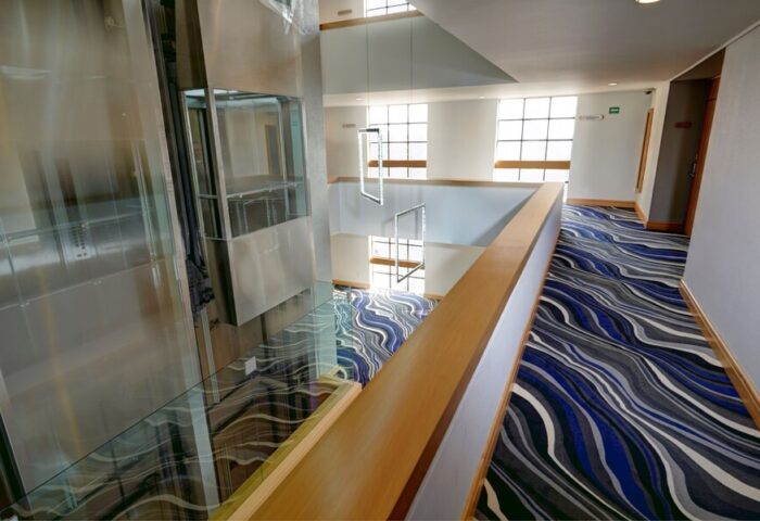 Hotel Royal Reforma's interior. A gay-friendly hotel in Zona. Modern design with a glass elevator, stylish carpet, and bright, open spaces.