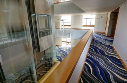 Hotel Royal Reforma's interior. A gay-friendly hotel in Zona. Modern design with a glass elevator, stylish carpet, and bright, open spaces.