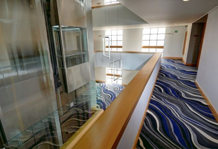Hotel Royal Reforma's interior. A gay-friendly hotel in Zona. Modern design with a glass elevator, stylish carpet, and bright, open spaces.