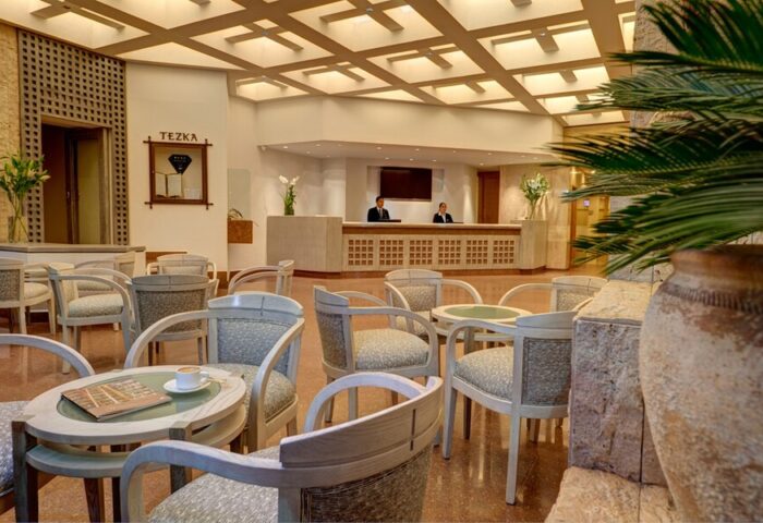 Hotel Royal Reforma lobby. Gay-friendly hotel in Zona. Seating area with chairs, tables, and plants. Reception desk with staff. Modern design.