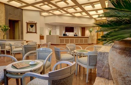 Hotel Royal Reforma lobby. Gay-friendly hotel in Zona. Seating area with chairs, tables, and plants. Reception desk with staff. Modern design.