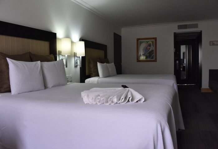 Hotel Royal Reforma gay-friendly room. Two beds with white linens, decorative towel, lamps, and artwork. Gay travel in Zona Rosa, Mexico City.
