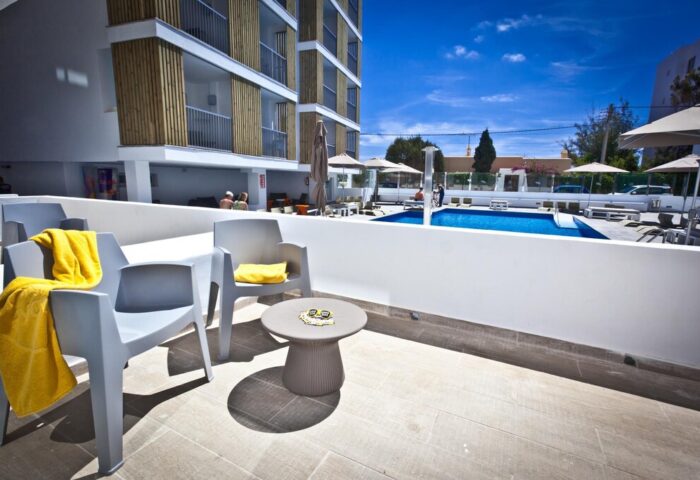 Ryans Ibiza Apartments adults-only gay-friendly hotel. Pool view from a balcony with chairs and a table. Great for gay men travel.