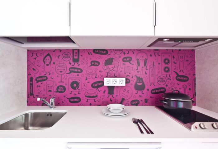 Ryans Ibiza Adults Only Apartments kitchen. Gay-friendly hotel with modern decor, pink backsplash with fun cartoon drawings. Perfect for LGBTQ+ travel.