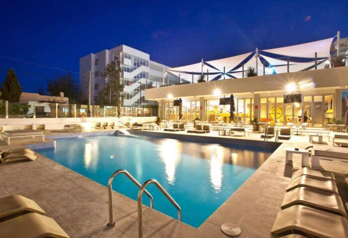 Ryans Ibiza Apartments pool at night. Gay-friendly, adults-only hotel with bar, lounge chairs, and modern design. Ideal for gay travel.