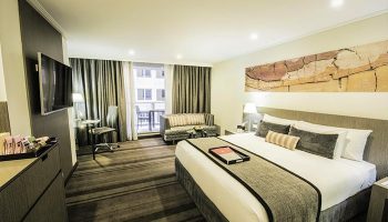 Rydges World Square gay-friendly hotel room. Modern design with a king bed, balcony, desk, & sitting area. Ideal for gay travelers.
