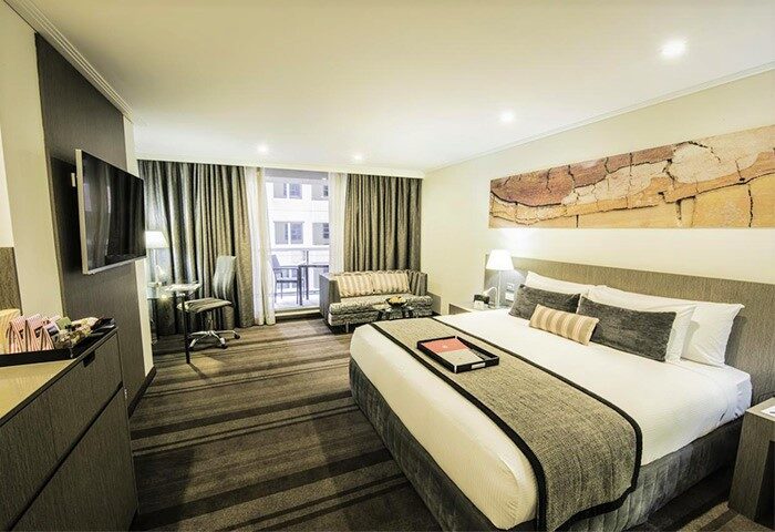 Rydges World Square gay-friendly hotel room. Modern design with a king bed, balcony, desk, & sitting area. Ideal for gay travelers.