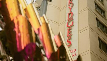 Rydges World Square, a gay-friendly hotel. The sign reads Rydges World Square in red letters. A modern art sculpture is in the foreground.