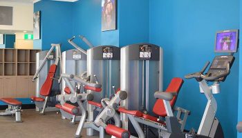 Rydges World Square gay-friendly hotel gym. Exercise machines with red cushions against a blue wall. Fitness center at this Sydney hotel.
